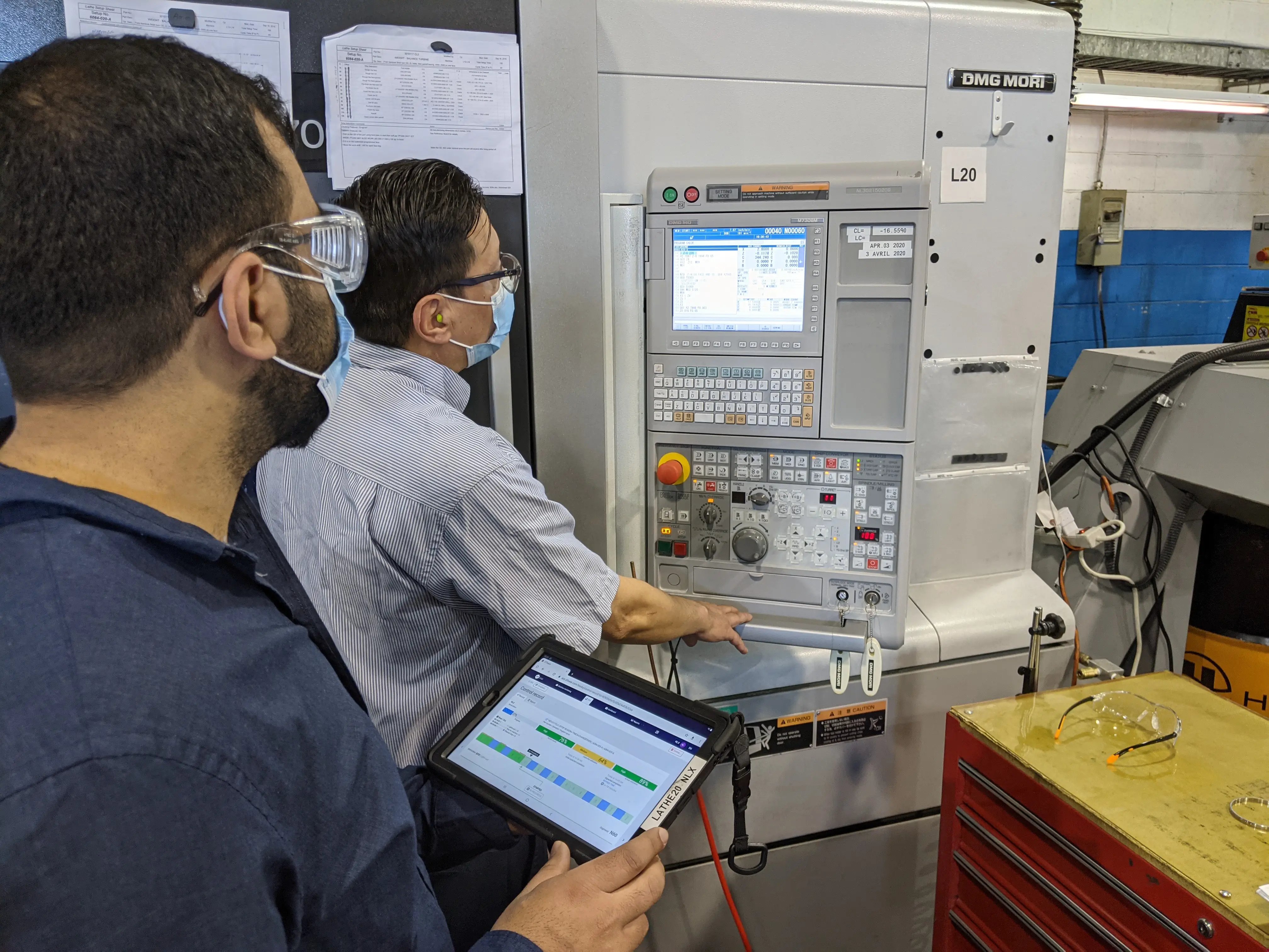 CNC operators and supervisors looking at the CNC control of the machine