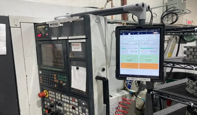 Tablette affichant une interface MES JITbase montée sur une machine CNC pour le suivi en temps réel de la production en atelier.