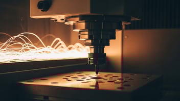CNC spindle machining a metal plate with visible sparks, illustrating real-time machine monitoring, OEE tracking, and performance optimization powered by JITbase.