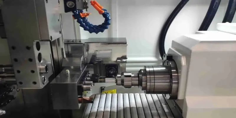 CNC machine tool performing a machining operation with spindle and workpiece visible, illustrating real-time production monitoring and machine performance tracking with JITbase.