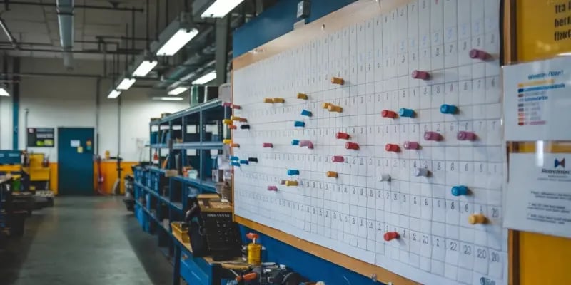 Manual production planning board with color-coded magnets used to track job scheduling and progress in a JITbase factory workshop.