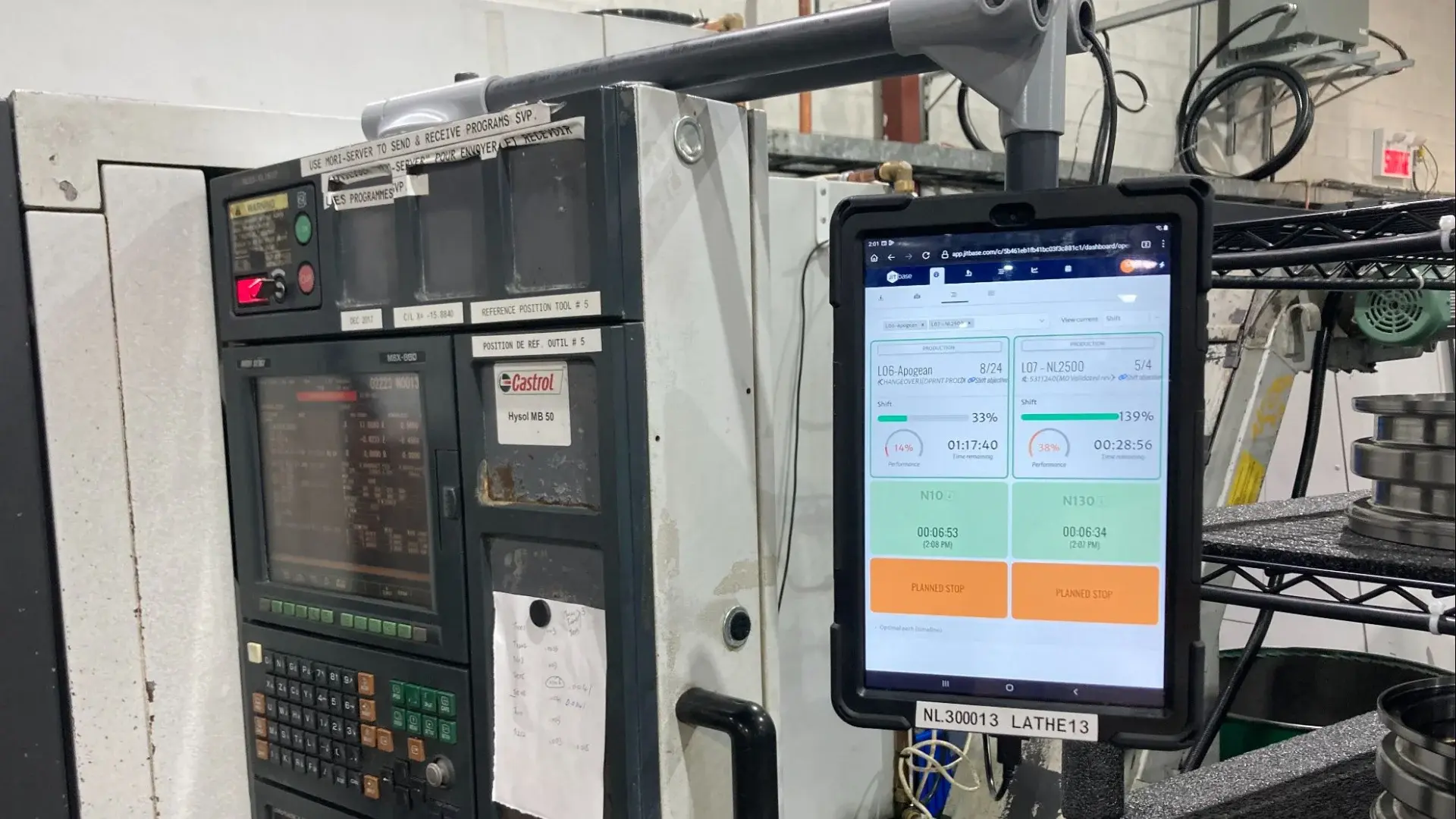 Tablet mounted next to a CNC machine control showing production status and planned stop buttons: recording stops for MTBF with JITbase